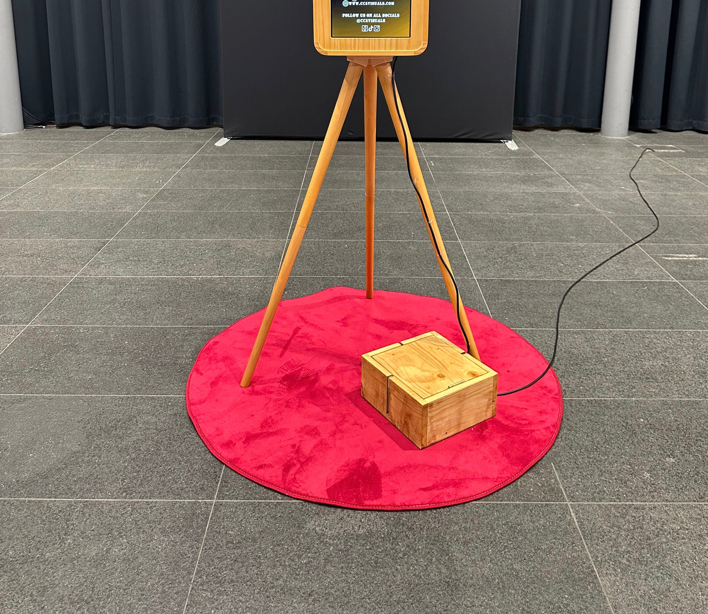 Wooden printer box on a red mat with a Vintage Double Screen DSLR iPad Selfie Pod Photobooth in the background