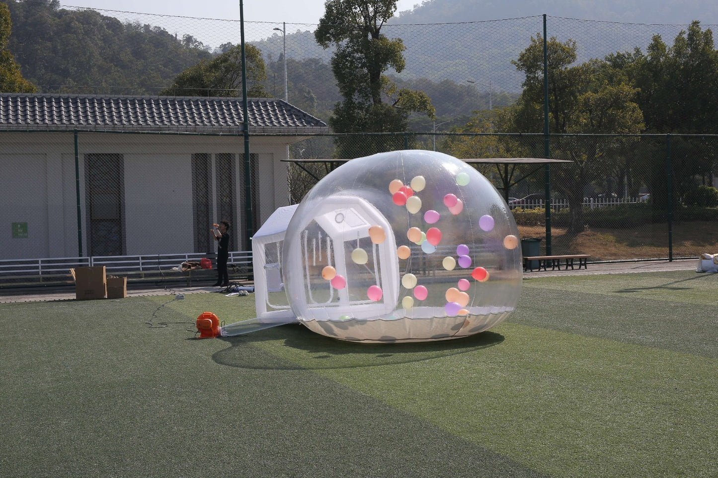 A clear inflatable dome-shaped bubble-house with colourful balloon inside for birthdays, celebrations, weddings, childrens birthdays