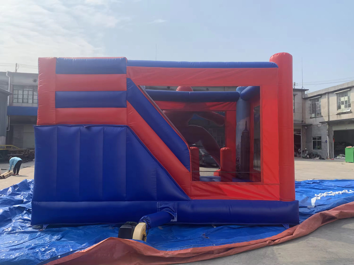 A large Spider-Man themed inflatable bouncy castle with a slide, predominantly in red and blue colours, designed for children's parties and events.