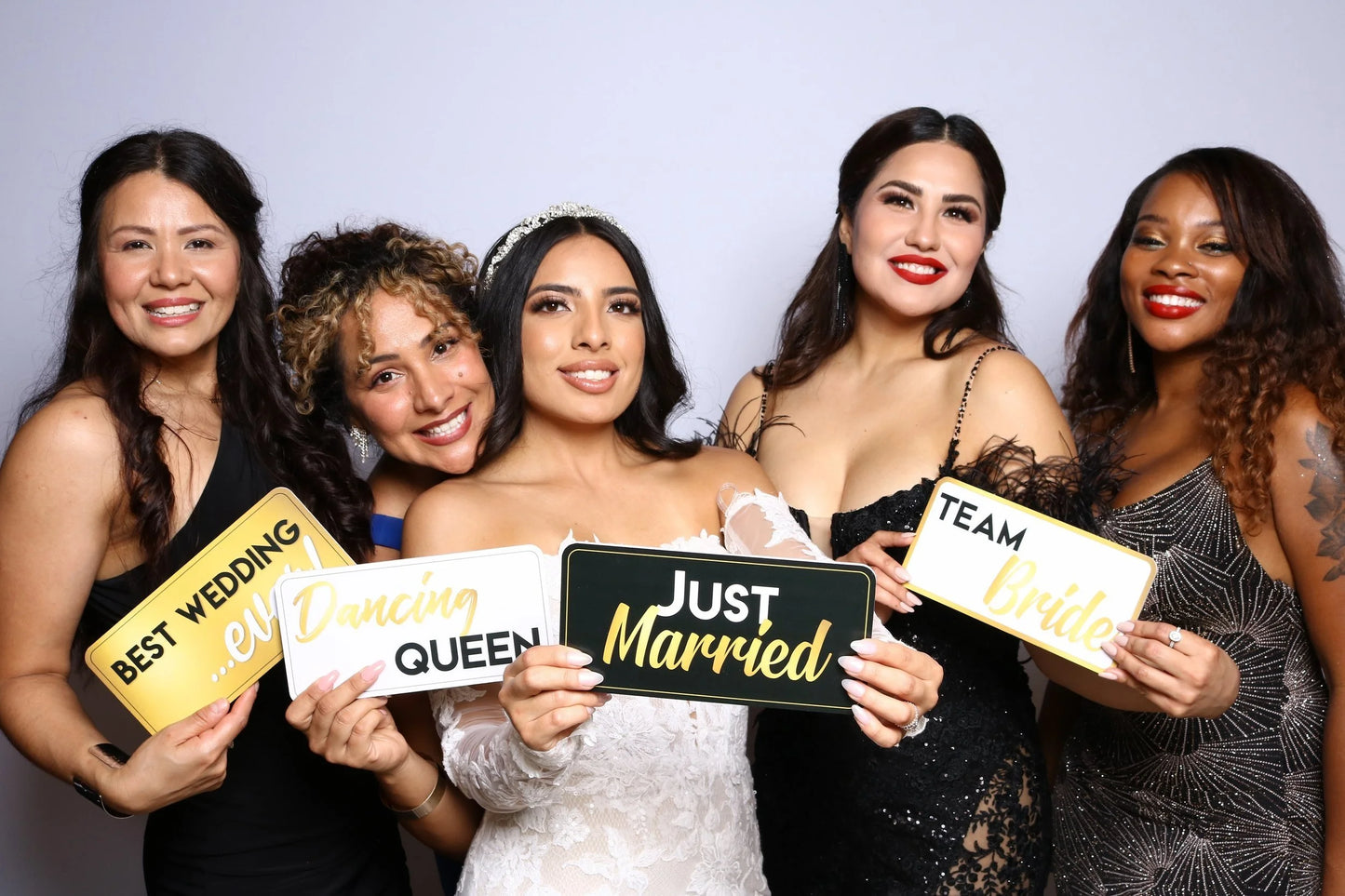 Group of women holding signs with wedding-related phrases against a plain background