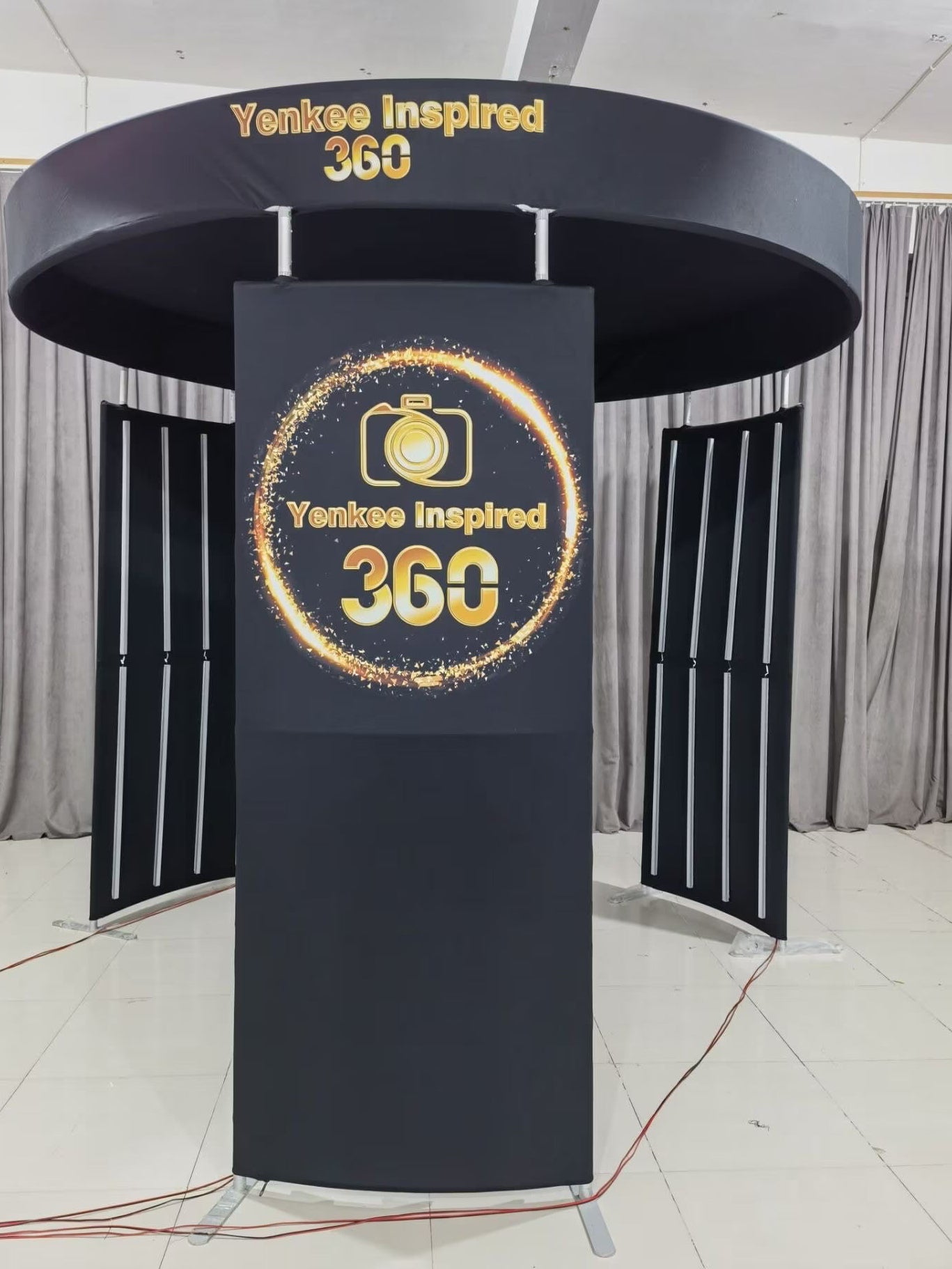 A black, circular, three-piece photobooth enclosure with integrated LED lighting, displayed against a white background.