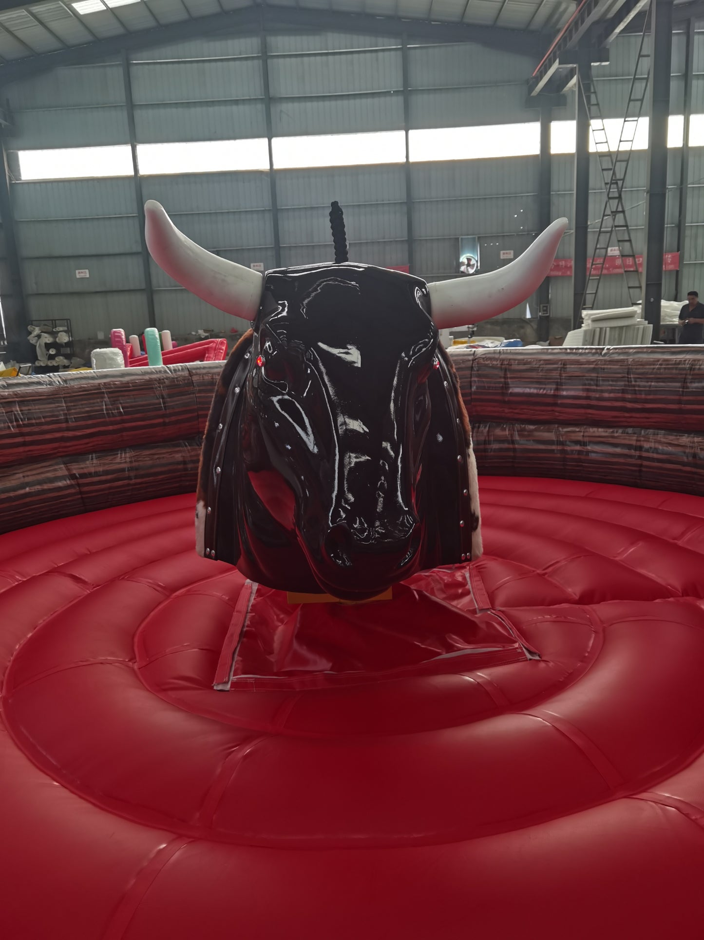 Black mechanical bull on a red platform in an indoor arena.