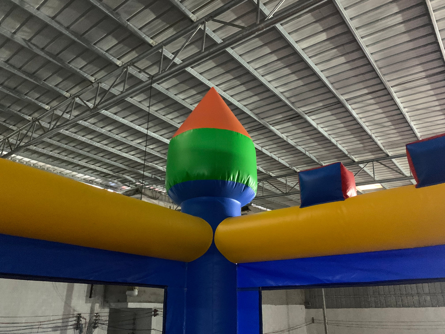 Colorful inflatable bouncy castle with a pointed top in an indoor setting