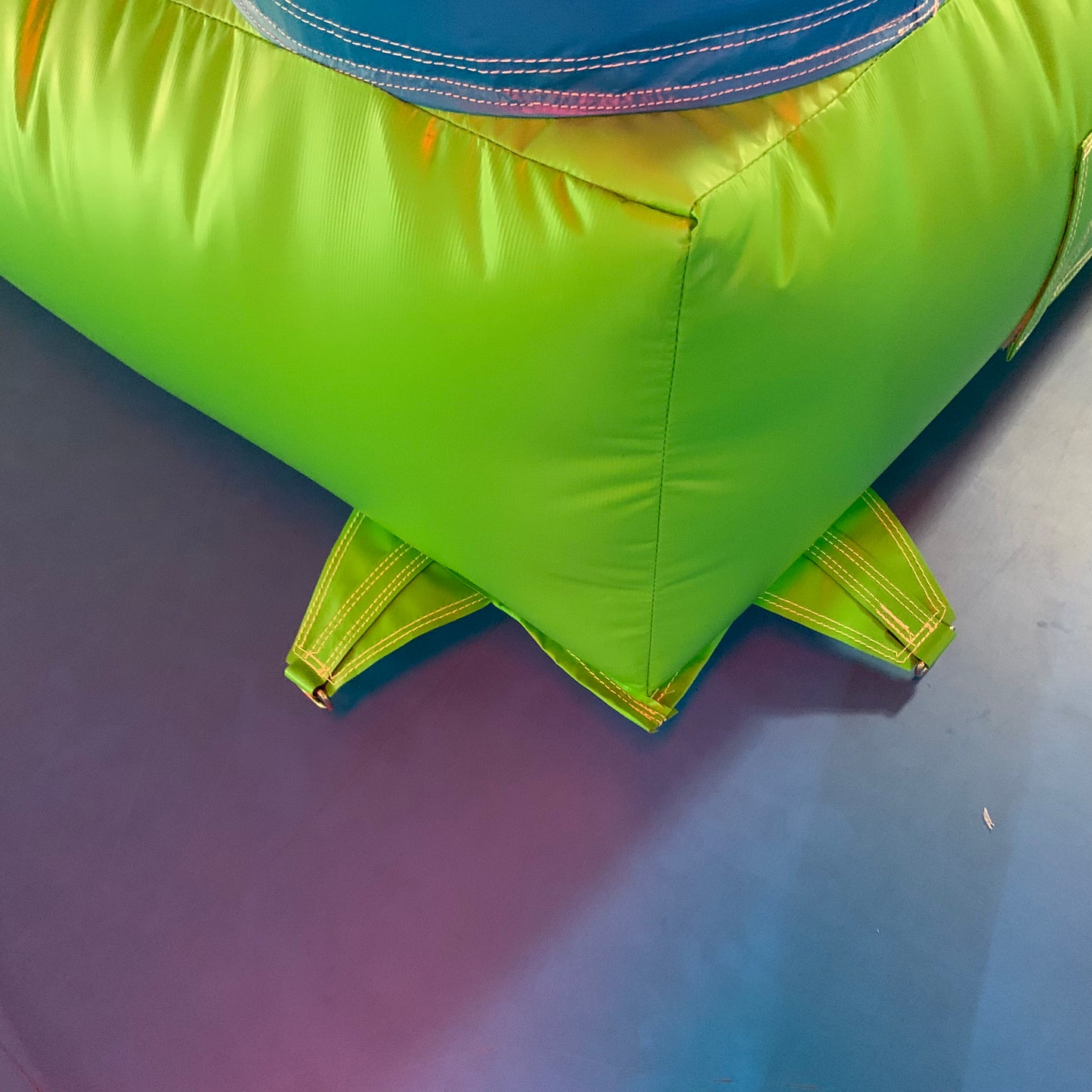 Close-up of a green and blue inflatable bouncy castle corner on a purple floor.