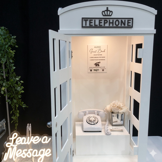 White phone booth with vintage telephone and decorative items on a black background