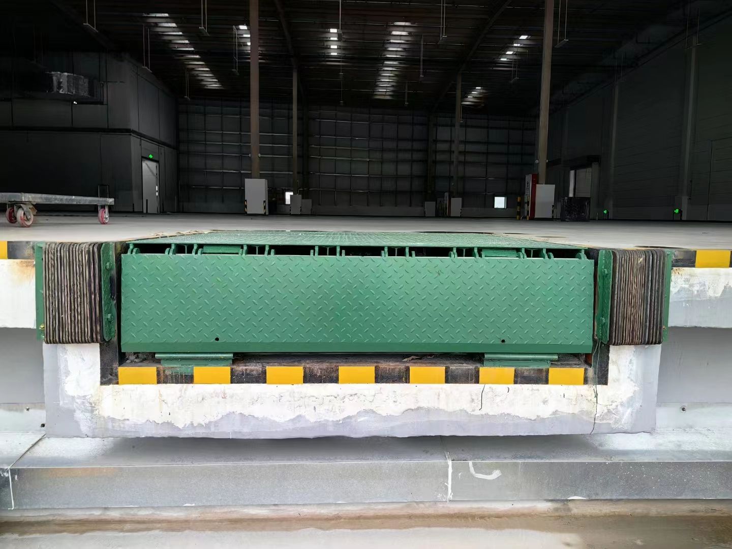 Loading dock with a green and black platform in a warehouse setting