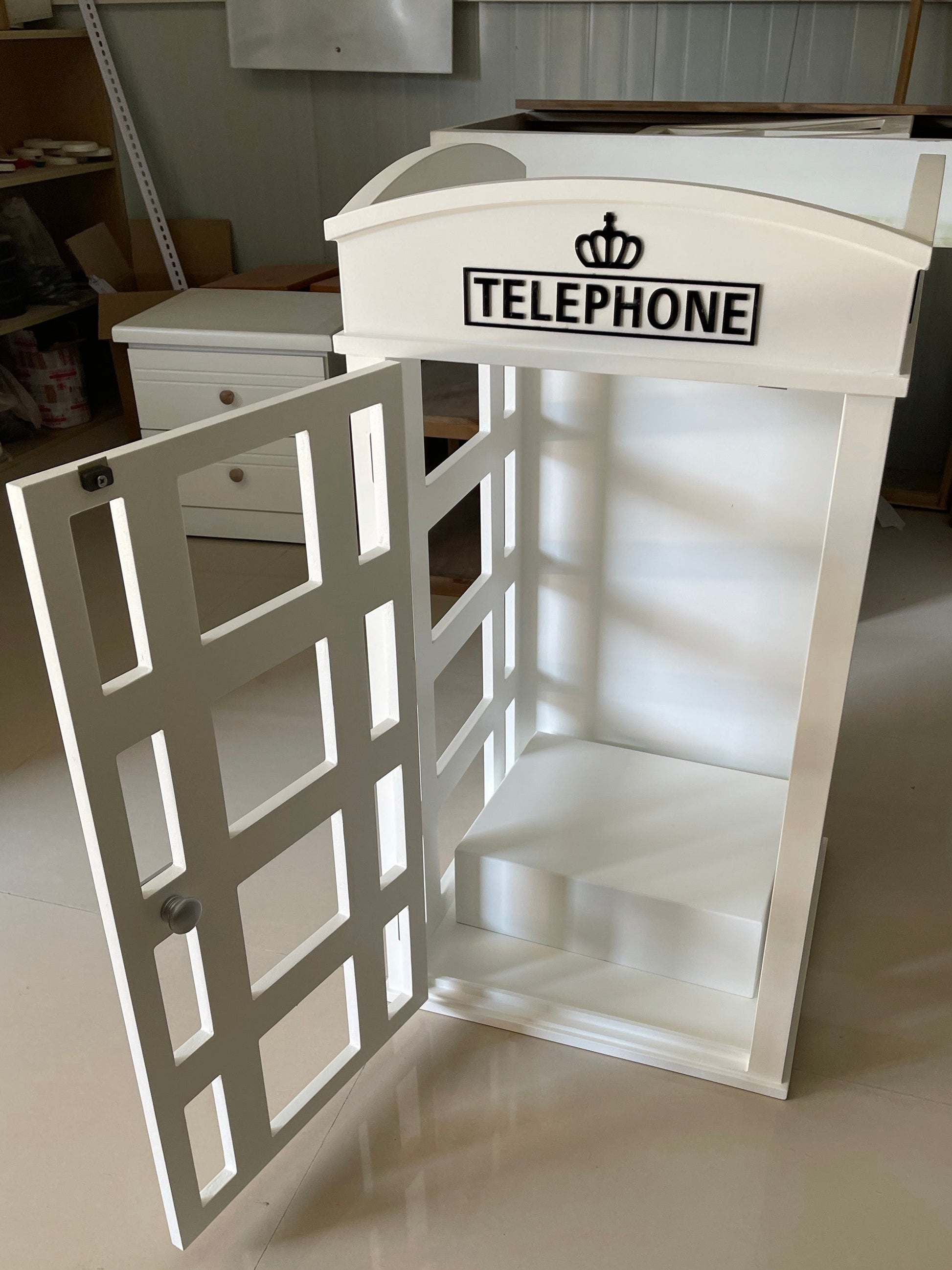 Vintage-style telephone booth with 'TELEPHONE' sign on a white wall.