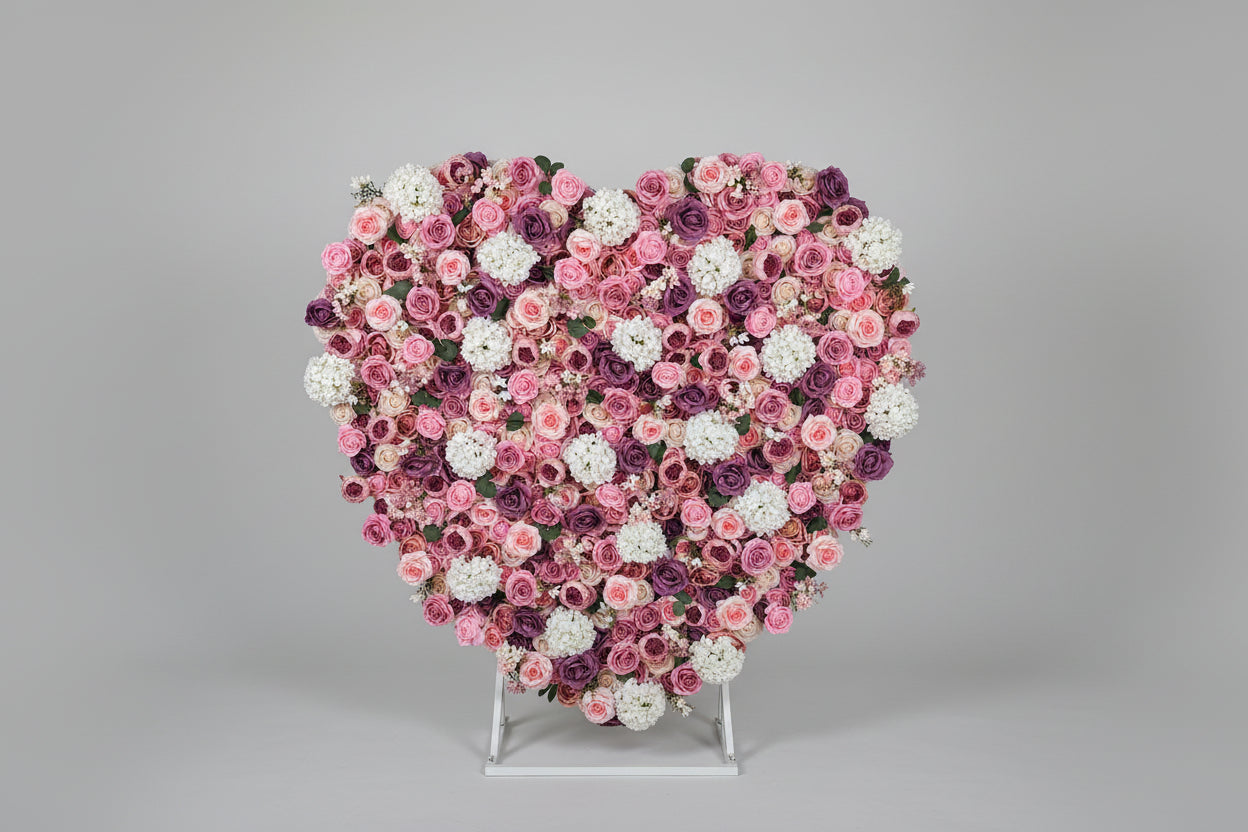 Heart-shaped arrangement of pink, white, and purple flowers on a gray background