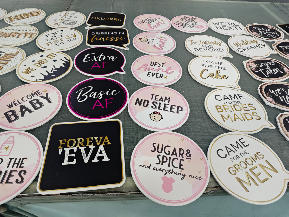 Collection of various photoboooth props with different designs and text on a surface.