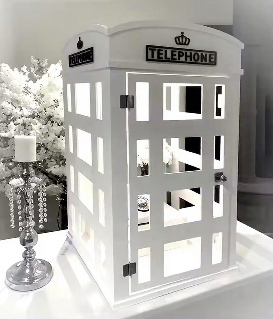 White phone booth-shaped cabinet with decorative elements on a white surface.
