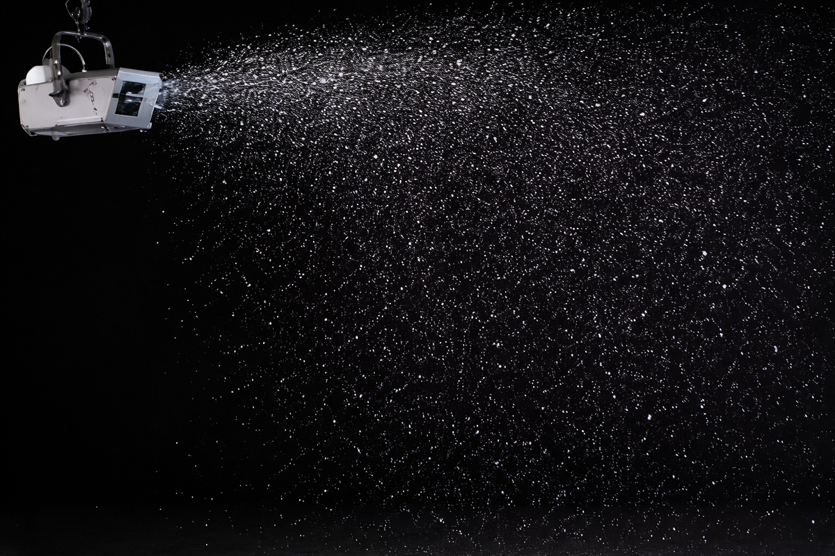Snow machine emitting snowflakes against a dark background