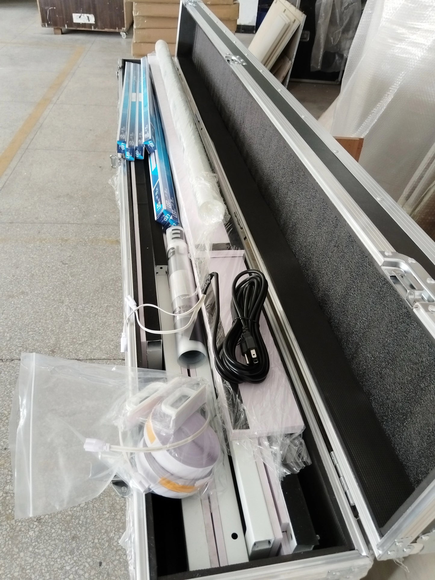 Large rectangular object with components inside a metallic case on a concrete floor.