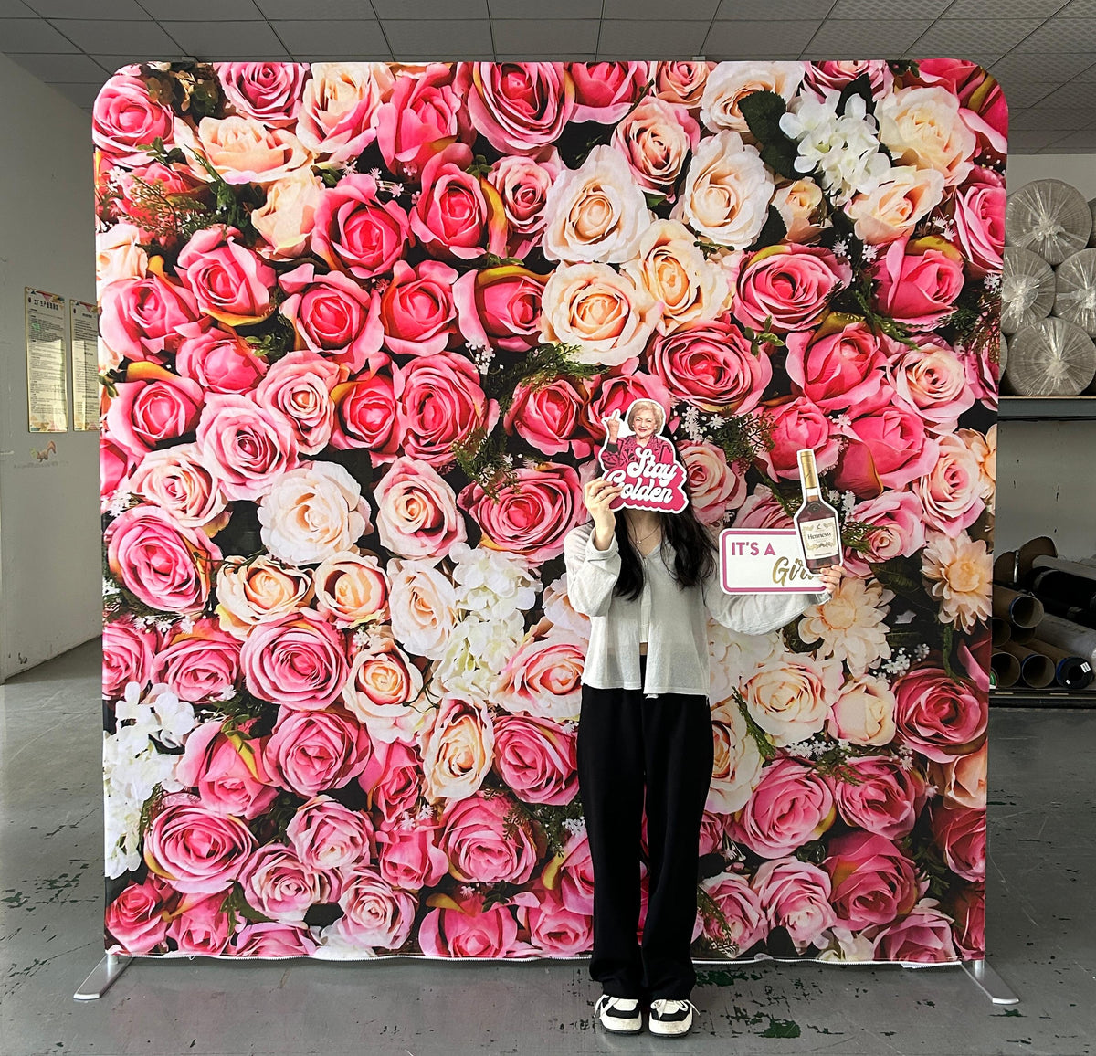 Person holding baby shower props in front of a floral backdrop