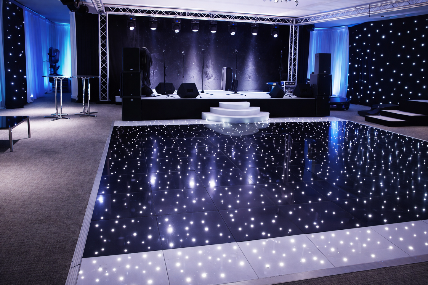 Black Starlit LED Dance Floor in a large indoor event space with stage and lighting equipment.