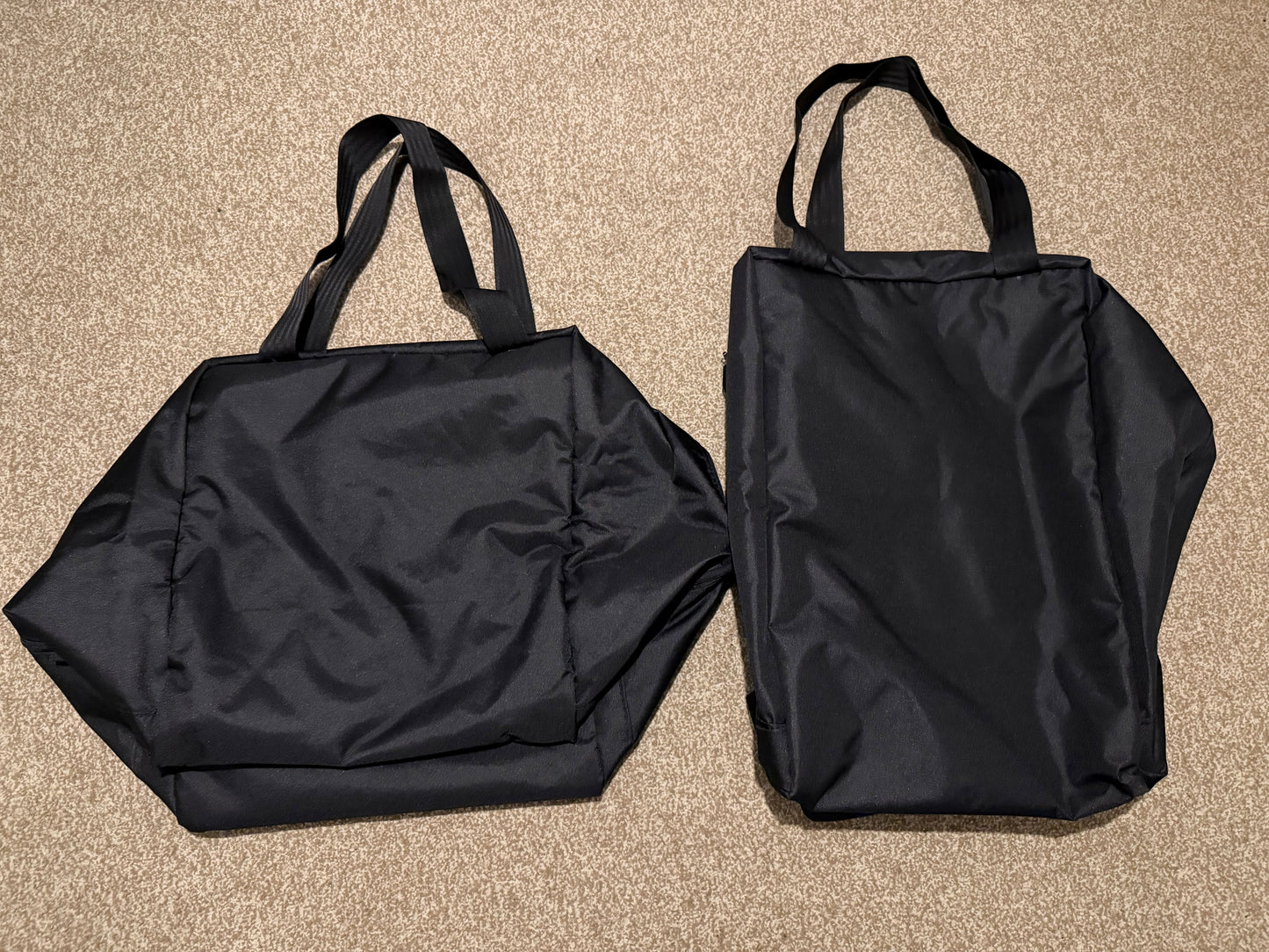 Two black bags, one folded and one unfolded, on a beige carpet.