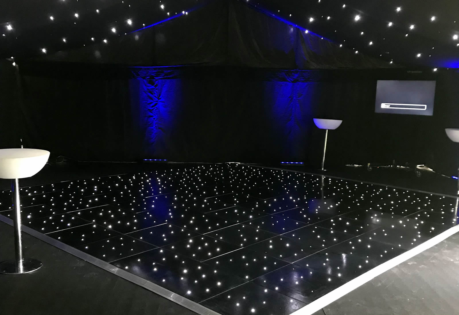 Black starlit dance floor with blue lighting in a venue.