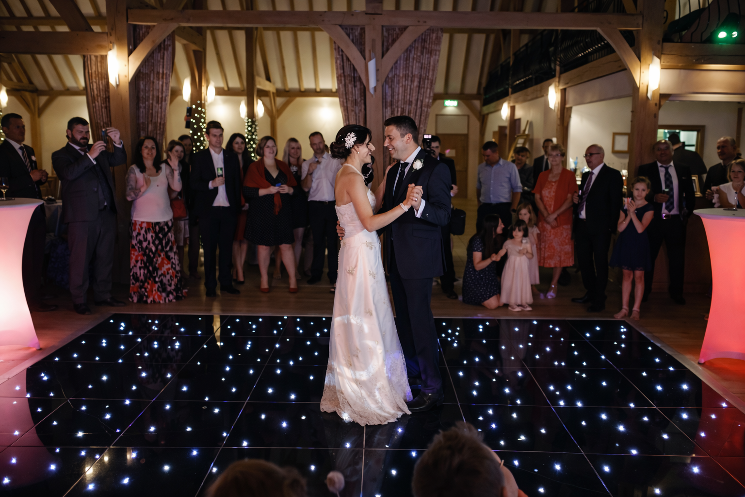Wedding couple dancing on a starlit dance floor with guests in the background.