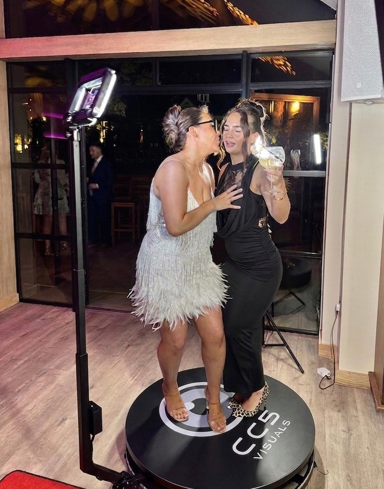 Two women interacting with a photo booth at an event.