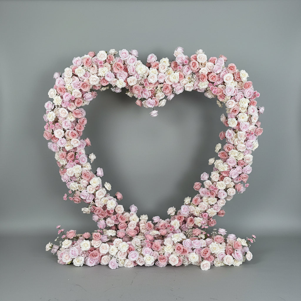 Heart-shaped arrangement of pink and white flowers on a gray background