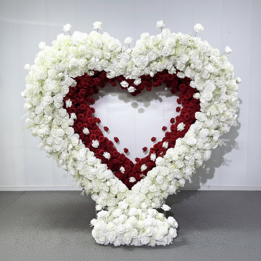 Large floral arch made of white and red flowers used for proposals and weddings set against a white studio background