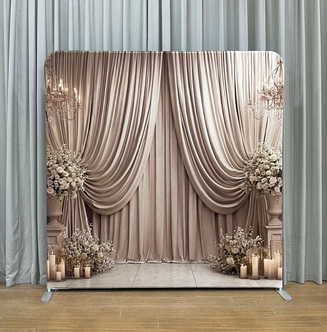 Decorative backdrop with draped curtains, flowers, and candles in a room setting.