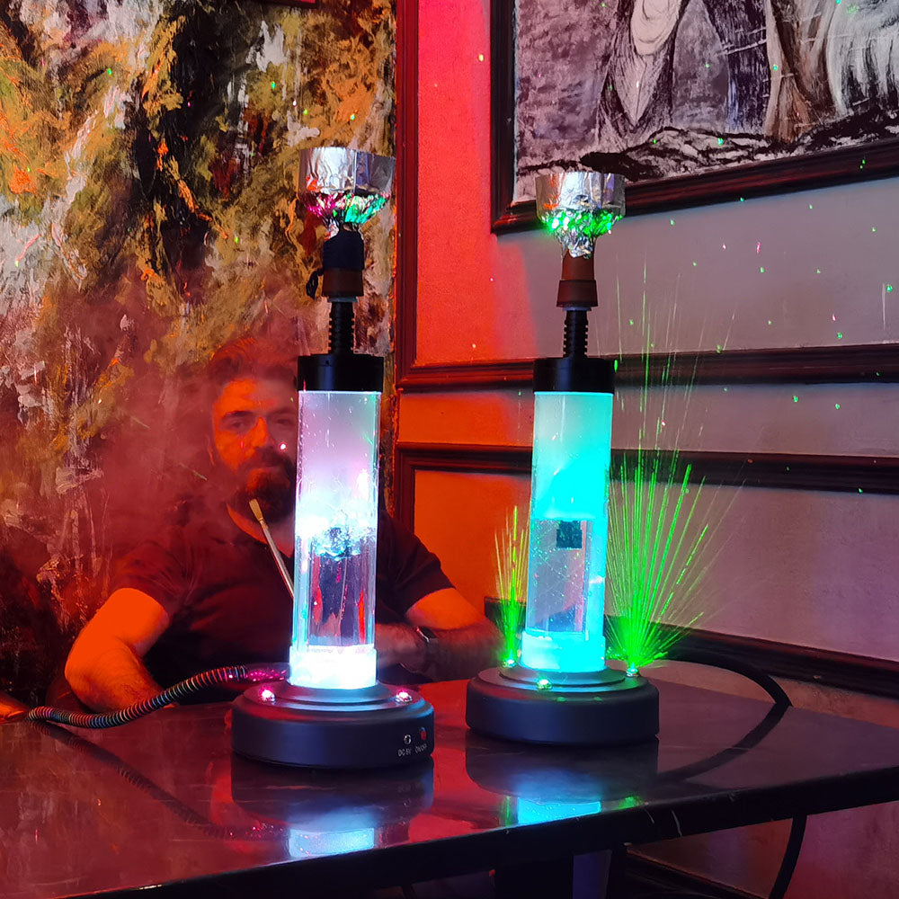 Two colorful hookah, shisha pipes with green lasers on a table with a person in the background.