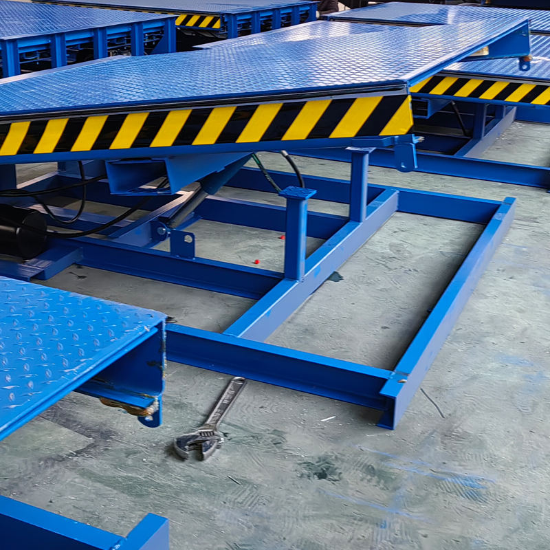 Blue hydraulic telescopic dock leveler and black hazard stripes on a concrete floor.