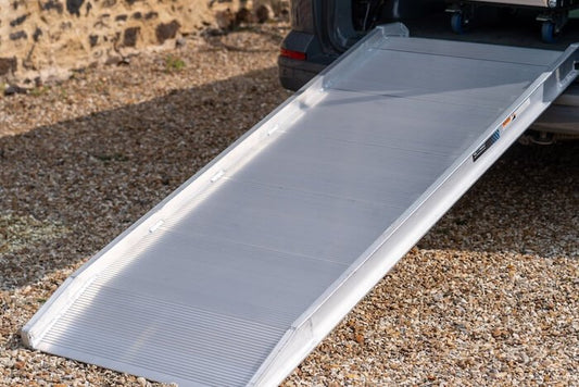 Foldable ramp suitable for large equipments, wheelchairs extended on a gravel surface.