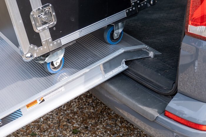 Foldable ramp suitable for large equipments, wheelchairs extended on a gravel surface.