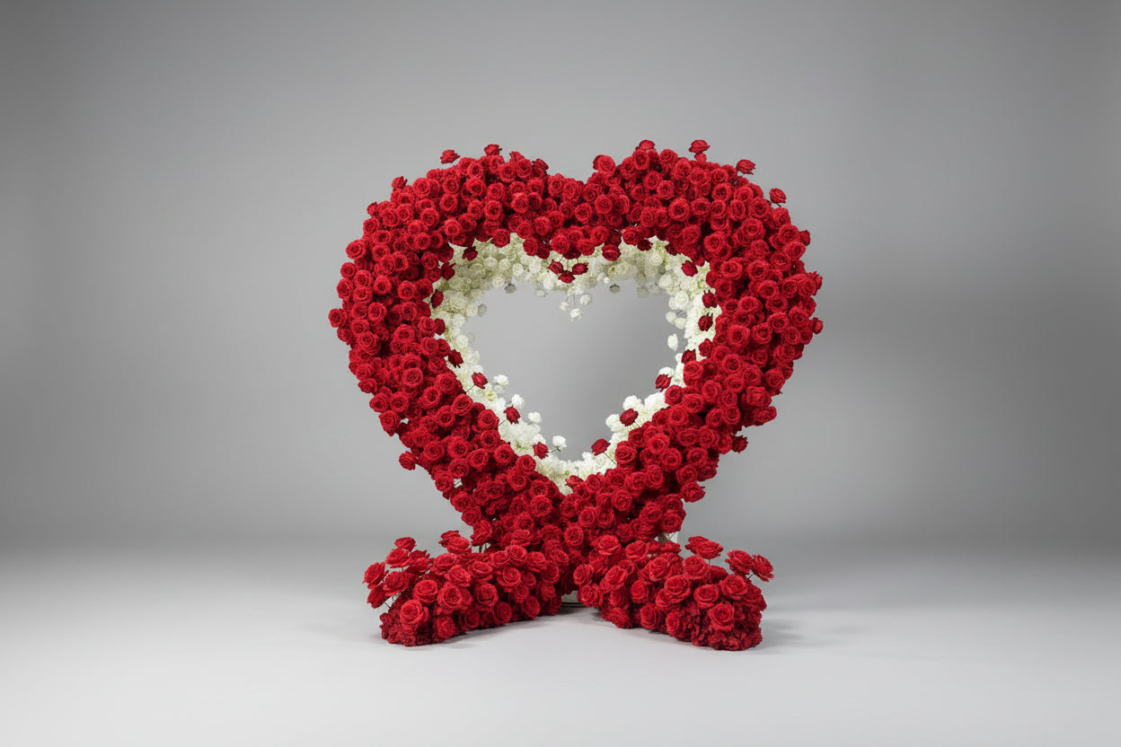 Heart-shaped arch arrangement of red and white flowers on a gray background