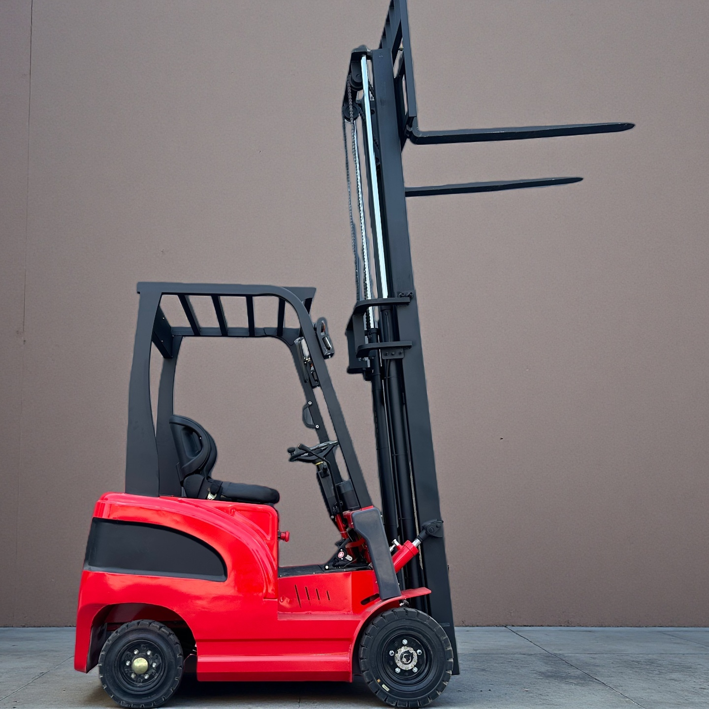 Red forklift with wheels in front of a grey industrial building