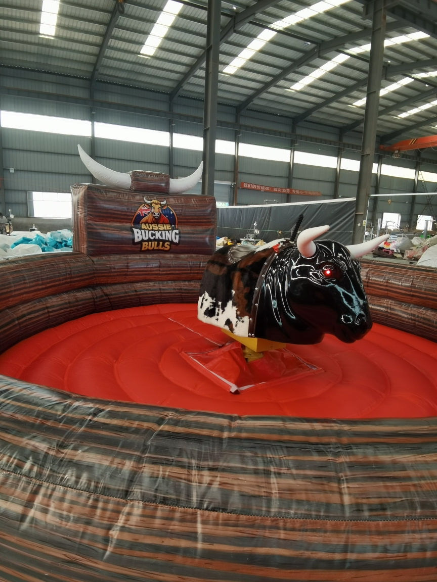 Black Inflatable mechanical bull ride in an indoor arena with bucking bulls branding.