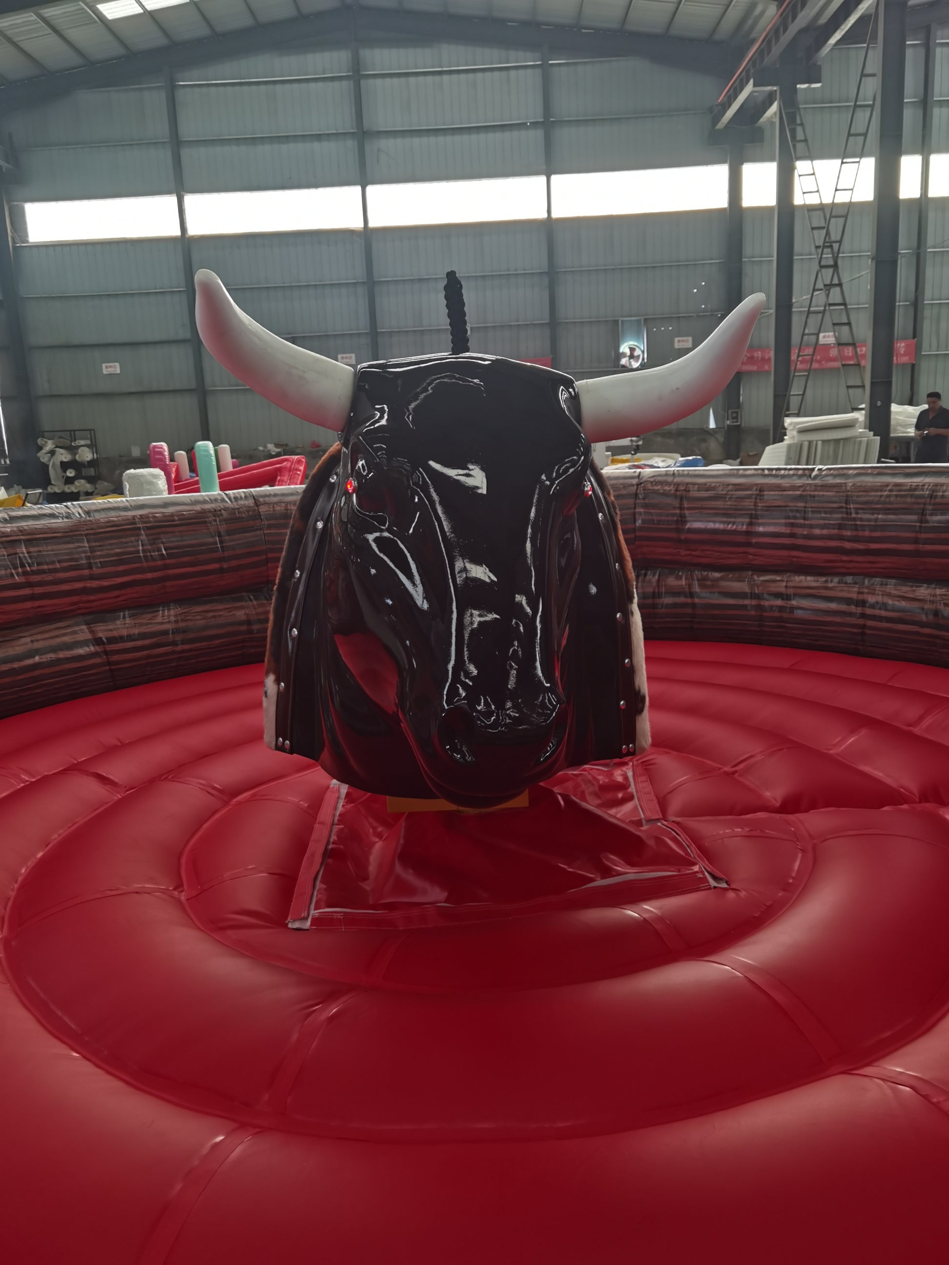 Black mechanical bull on a red platform in an indoor arena.