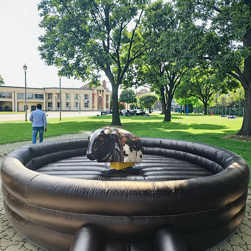 Black Inflatable mechanical bull in a park with trees and buildings in the background