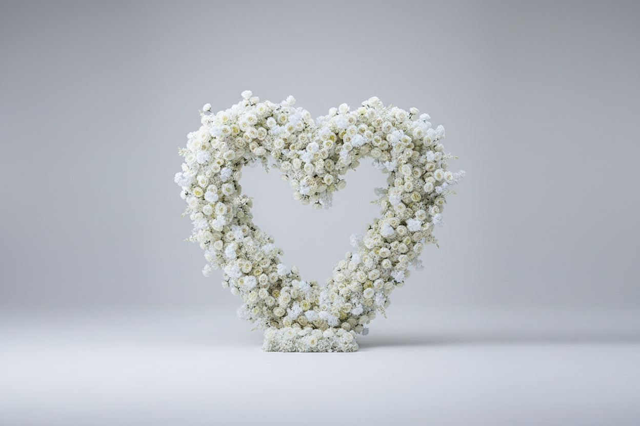 Large floral arch made of white flowers used for proposals and weddings set against a white studio background