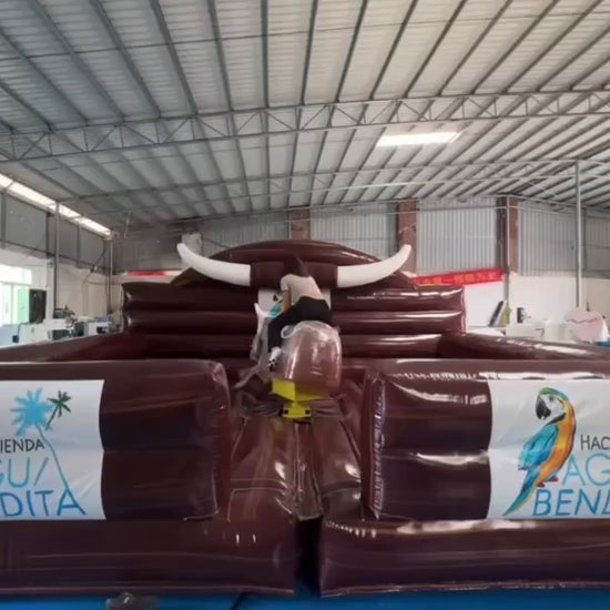Woman riding a black mechanical bull with a brown inflatable enclosure.
