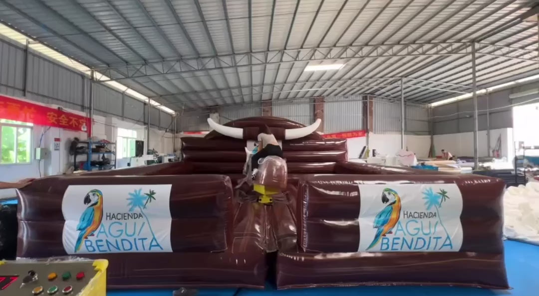 Woman riding a black mechanical bull with a brown inflatable enclosure.