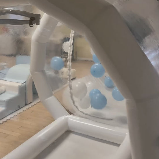 A clear inflatable dome-shaped bubble-house with colourful balloon inside for birthdays, celebrations, weddings, childrens birthdays 